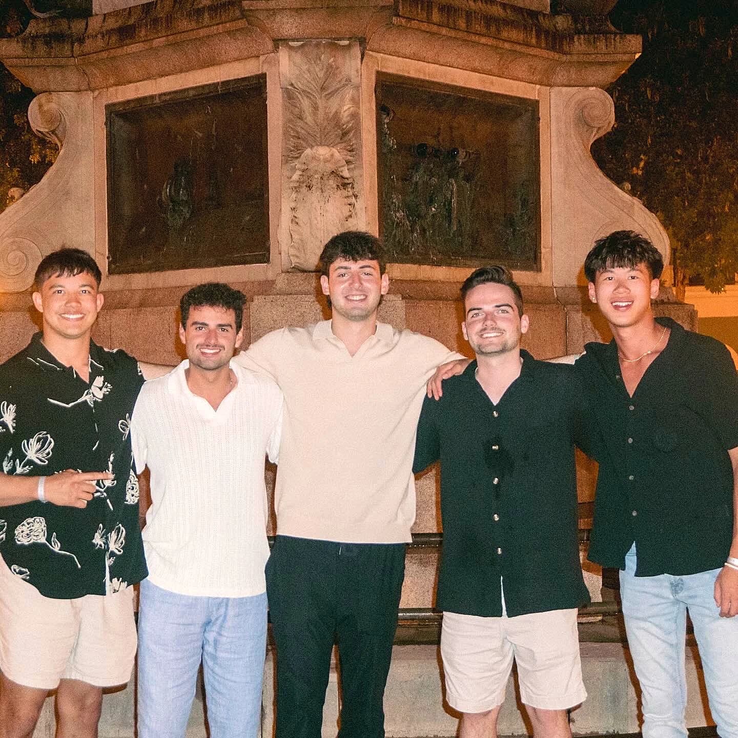 Five friends in front of a stone monument in San Juan at night.